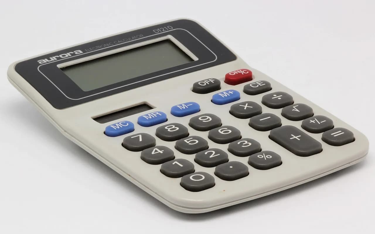 Une calculatrice de bureau posée de trois quarts sur un fond blanc.