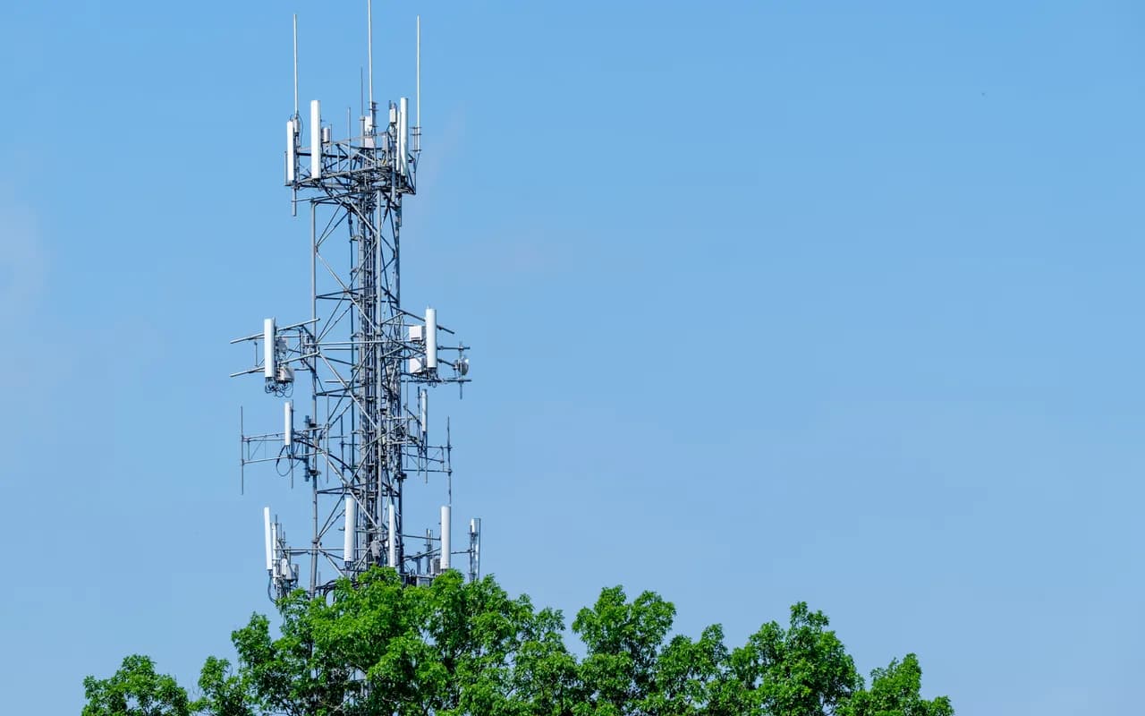 Pylône de téléphonie mobile garni de panneaux d’antennes, sur ciel dégagé.