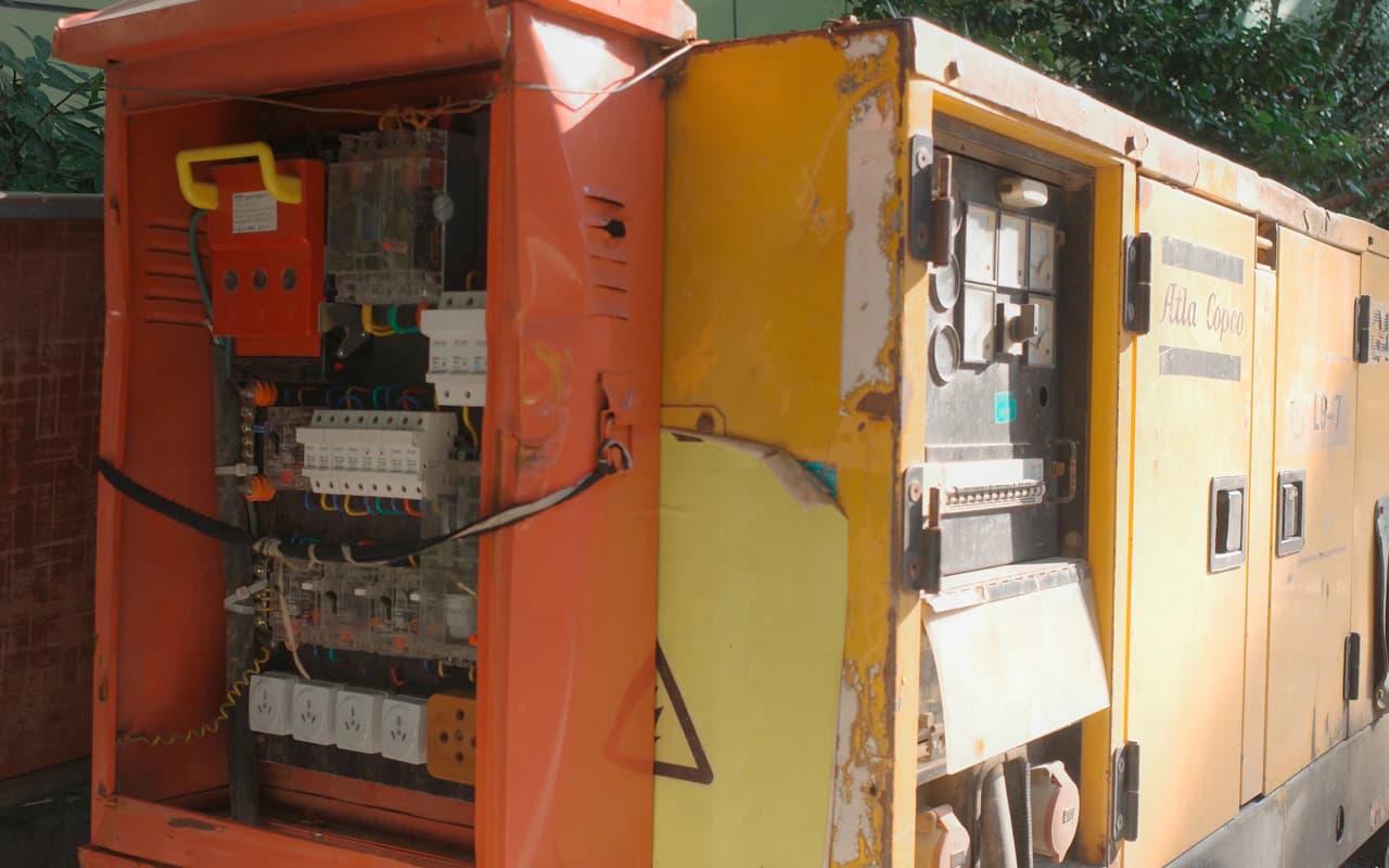 Groupe électrogène industriel jaune, capot ouvert sur son tableau électrique.